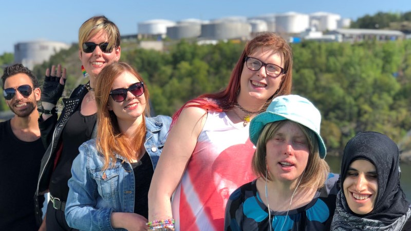 Sex personer står på rad i solen, i bakgrunden syns industribyggnader på en grön kulle. Det är styrelsen för US Stockholm. Rakel Eriksson står näst längst till höger i ljusblå hatt och blå klänning.