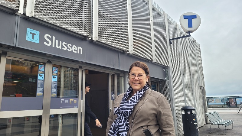 Utanför entrén till Slussens tunnelbanestation står en kvinna med långt brunt hår, Eva Rosman.