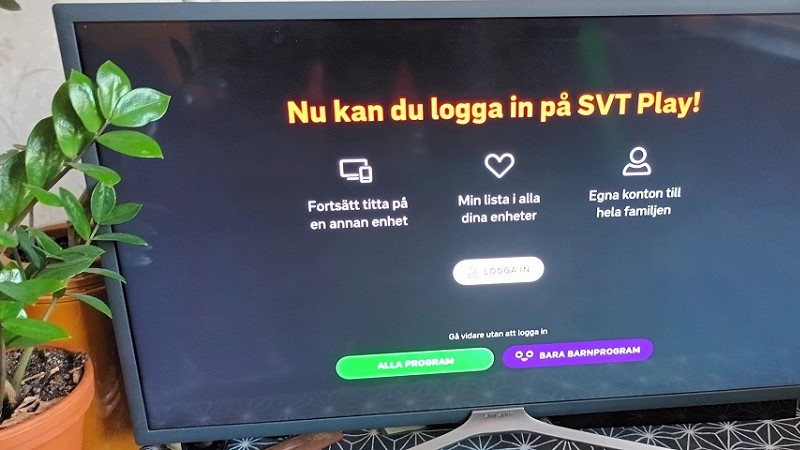 Inloggningssidan till SVT Play på en teveskärm, till vänster står en grön krukväxt.