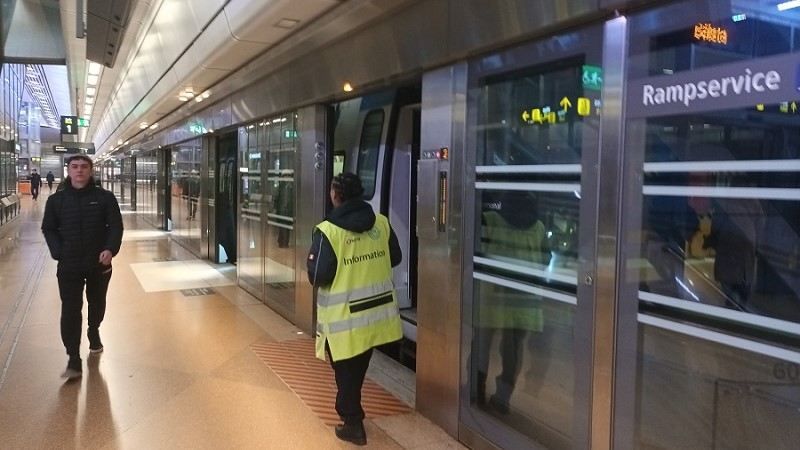 Ett pendeltåg står inne på Stockholm City. En person i neongul väst står med ryggen till vid tågdörren. Perrongen är tom förutom en man som kommer gående.