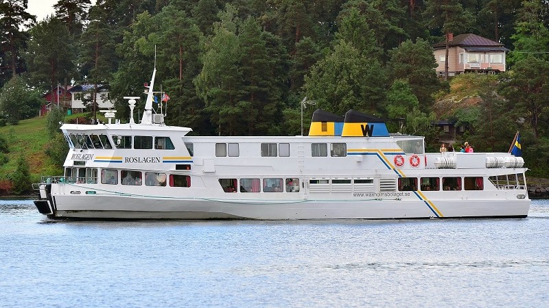 Fartyget M/S Roslagen framför en grönskande kuststräcka.