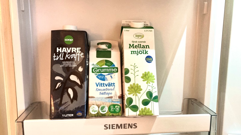 I en öppen kylskåpsdörr står tre snarlika kartongpackningar som liknar mjölkförpackningar.