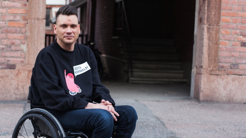 Anders Westgerd sitter i en rullstol framför en tegelvägg.