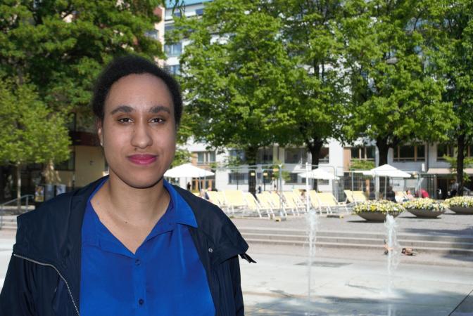 Aniké Kadiri är en av en handfull svenskar på utbildningen. Här syns hon iförd marinblå blus och mörkblå jacka. Hon har mörkt hår som är uppsatt. I Bakgrunden syns en fontän och grönska.