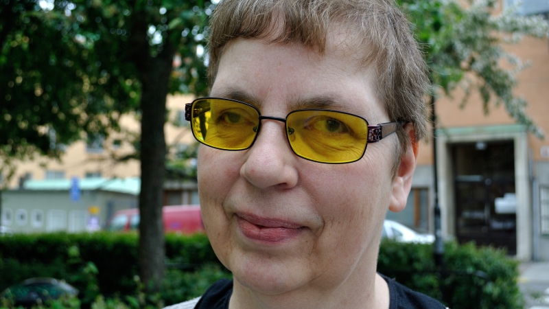 Anita Maddock har kort brunt hår och orangea glasögon.