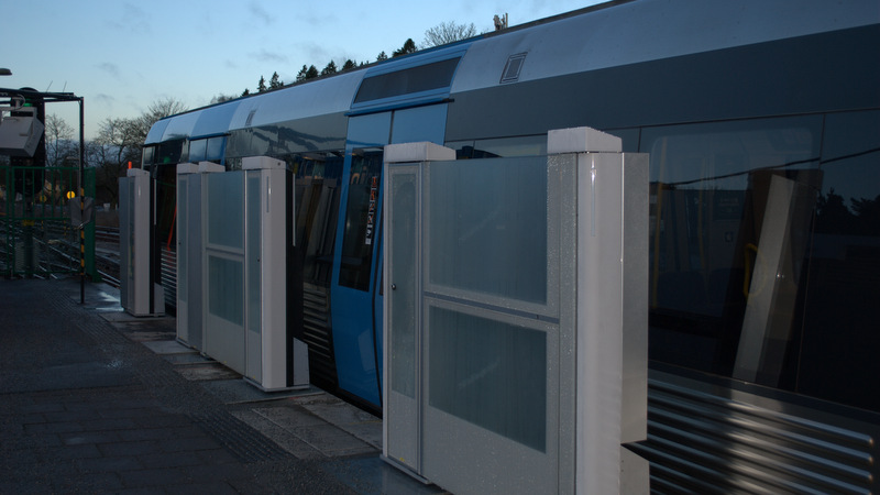 Plattformsdörrar i glas som öppnas för ett tåg.