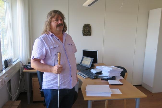 Håkan Thomsson, SRF.s ordförande, framför sitt skrivbord med dator och högar med punktskrift