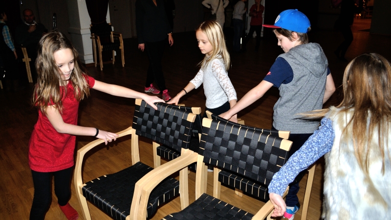 Fyra barn tar sig runt uppställda stolar i leken "Hela havet stormar"