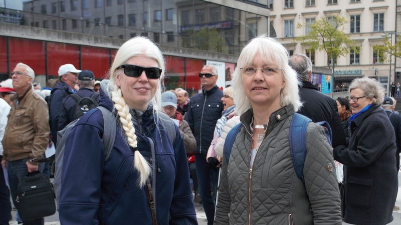 Två kvinnor framför en folkmassa. Anne-Lie Telning till vänster har det ljusa långa håret samlat i en fläta och mörka glasögon och Ditte Kahlström Jansson har kort blont hår, glasögon och grön jacka.