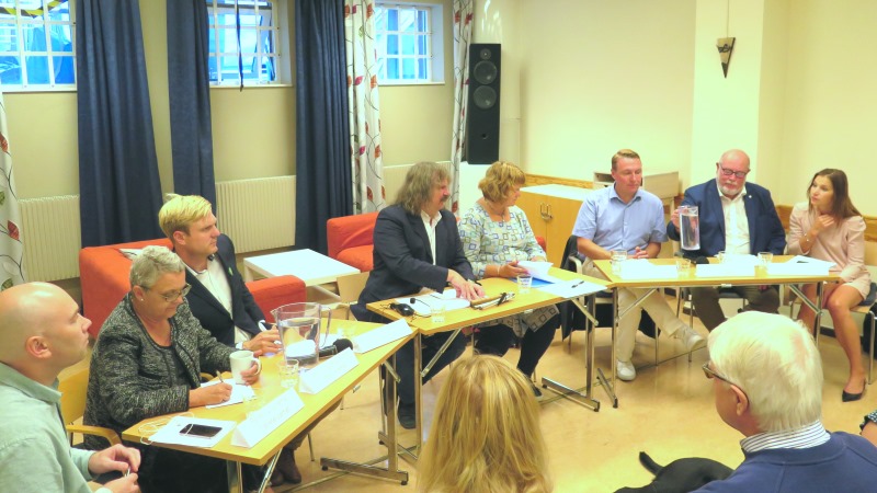 Landstingspolitiker på rad vid ett halvcirkelformat bord. I mitten moderatorn Håkan Thomson och distriktets ordförande Karin Hjalmarson.