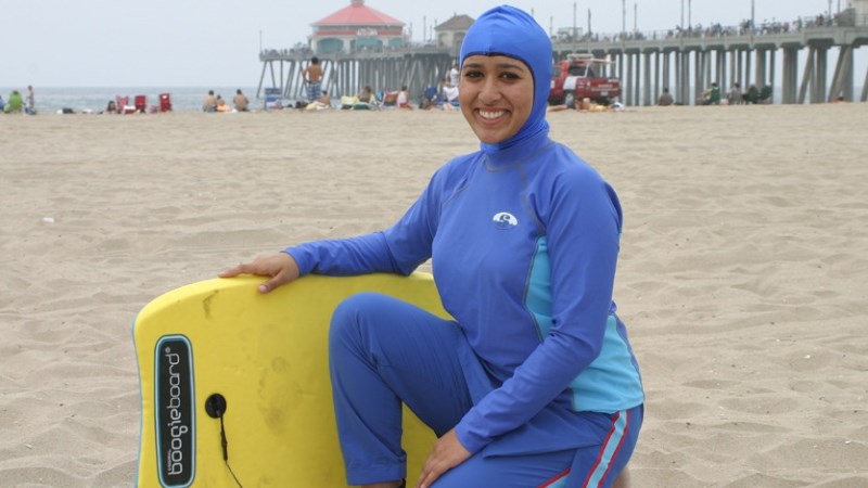 Kvinna i blå burkini på strand.
