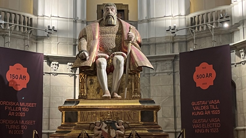 Stor staty i sten av Gustav Vasa, han sitter på en förgylld tron.