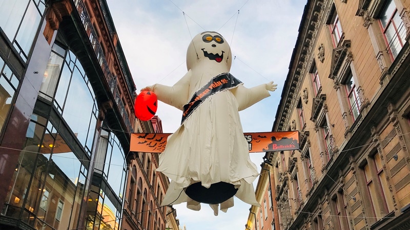 Mellan husen på drottninggatan i stockholm svävar ett över 2 meter stort uppblåsbart spöke i vitt som har en orange pumpa i handen. Det är utanför affären Buttericks. 