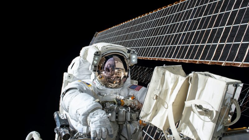 Vitklädd astronaut jobbar med solpanel i rymden