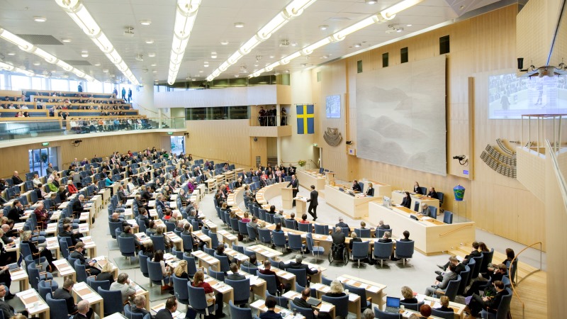 Riksdagsledarmöter som sitter och lyssnar på två debattörer inne i Sveriges riksdag.