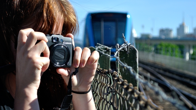 En kvinna filmar ett blått tunnelbanetåg.