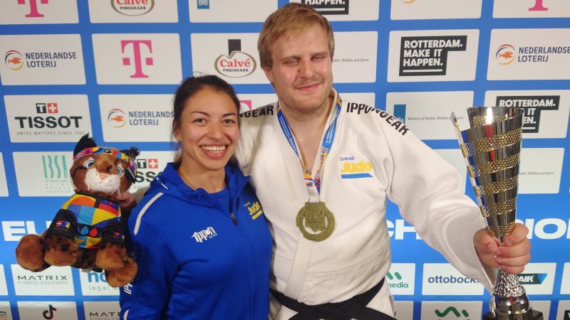 Mikaela-Barrera-Birath, t.h. Oscar Widegren och En vit ung man i vit judodräkt, guldmedalj runt halsen, guldfärgad pokal i hand. Bredvid står mörk kvinna i blå trängingskläder.