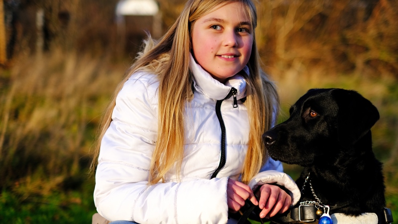 Ung flicka med ljust, långt hår, svart hund. Foto: Joachim Kåhlman 