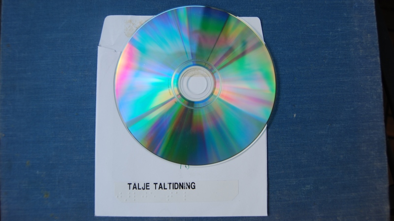 CD-skiva ligger på vitt cd omslag med text: Tälje taltidning. Blå bakgrund.