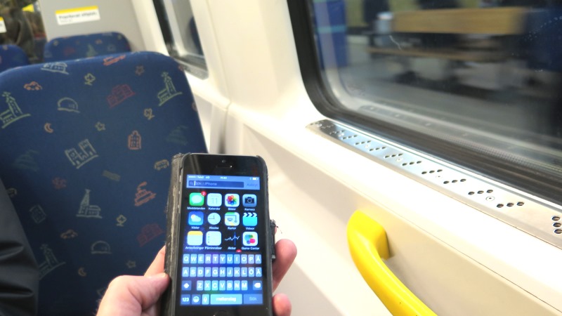 Bild på hand med mobil i tunnelbanevagn.