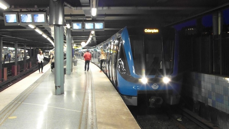 Perrong på Gamla stans tunnelbanestation, blått tåg kör in.