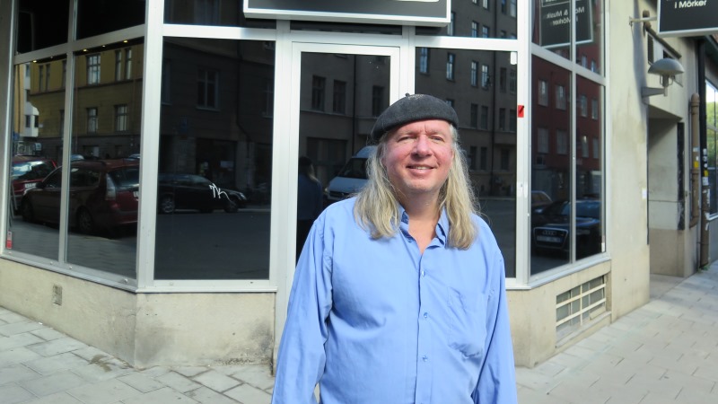 Ulf Nordquist i blå skjorta, långt grått hår och svart basker.